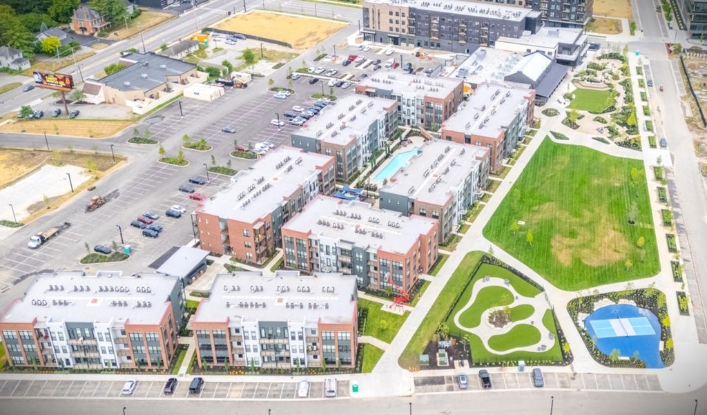 Overlooking Columbus apartments, this modern complex features multiple buildings surrounding a central swimming pool, complemented by parking areas and lush green spaces that include a small park and sports court.