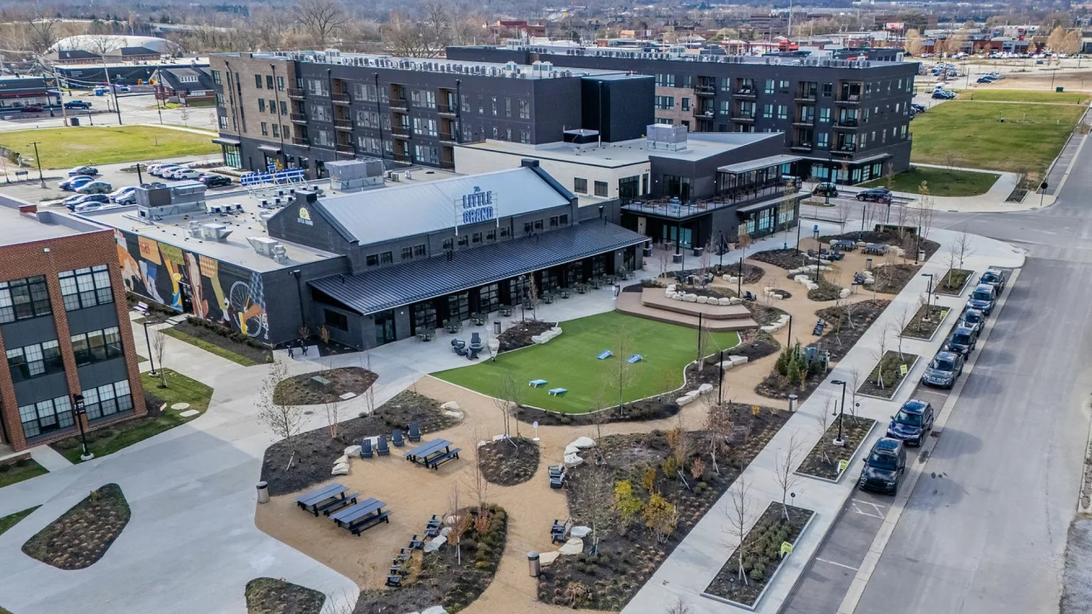 Aerial view of Columbus apartments reveals a modern urban complex featuring multiple buildings, green space, outdoor seating, and ample parking.
