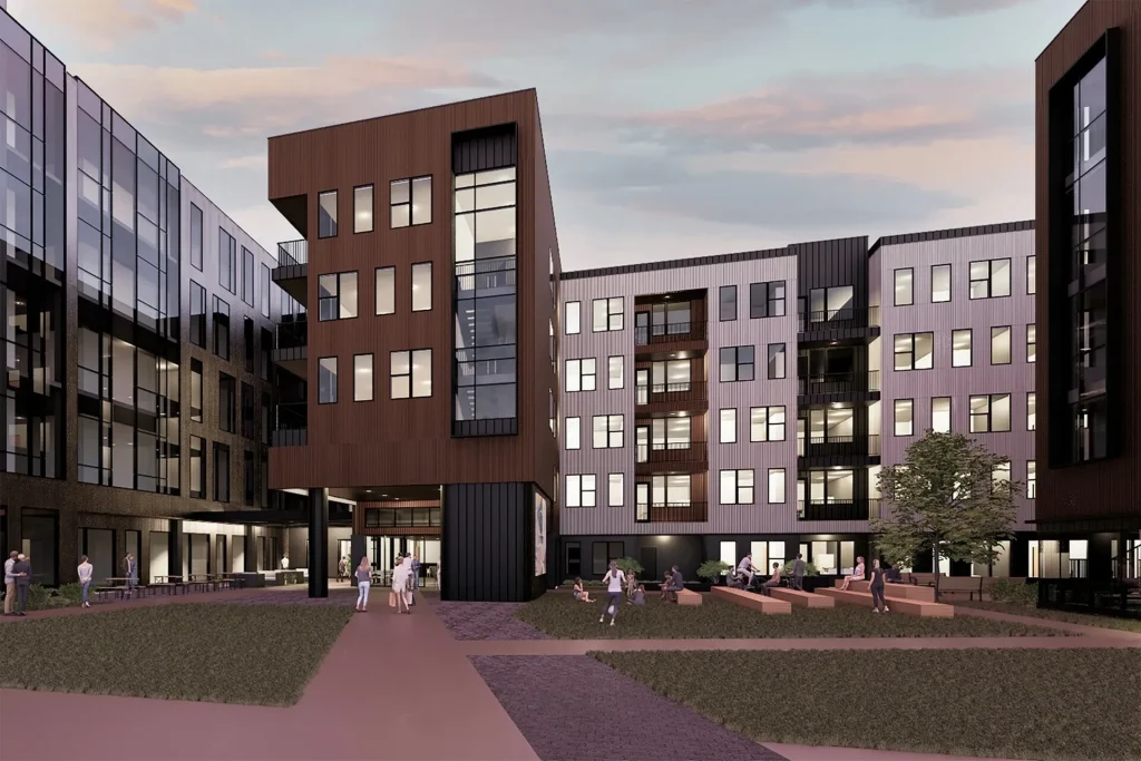 Modern apartment complex with angular architectural design, featuring large glass windows. People are gathered in the courtyard area with green spaces under a partly cloudy sky.