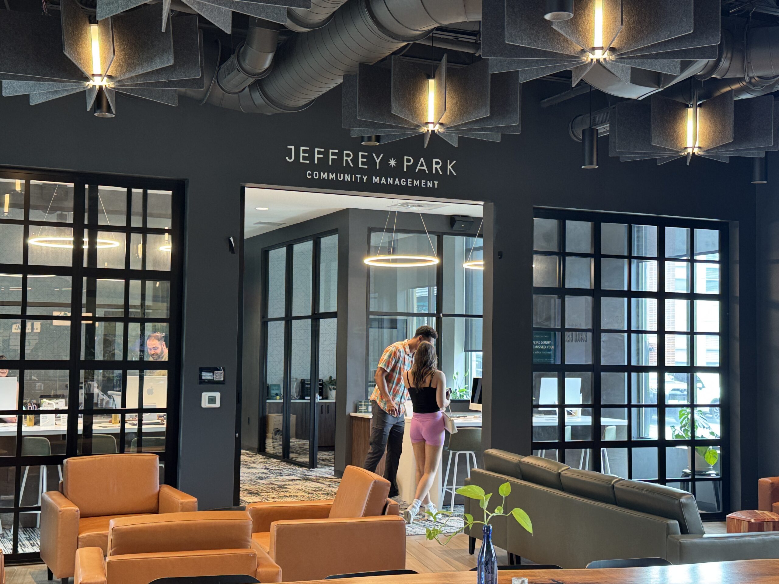 Thrive Companies, Two people stand at a counter inside the Jeffrey Park Community Management office, surrounded by modern furniture and stylish Jeffrey Park ceiling acoustic panels. Apartments in Columbus Ohio