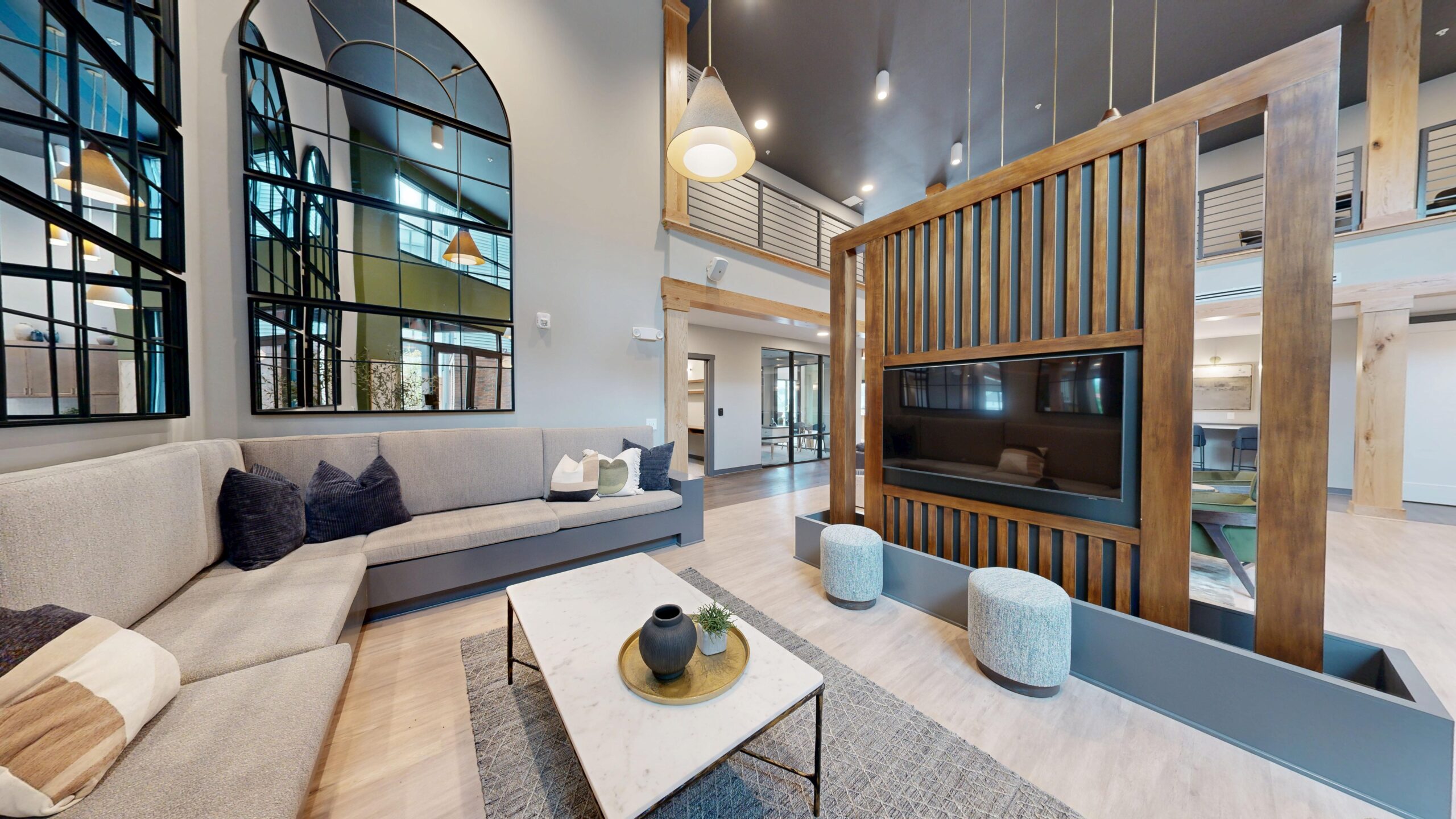 Modern Trace Quarter living room featuring a sectional sofa, marble coffee table, decorative pillows, large windows, wooden room divider with TV, and high ceilings with pendant lights.