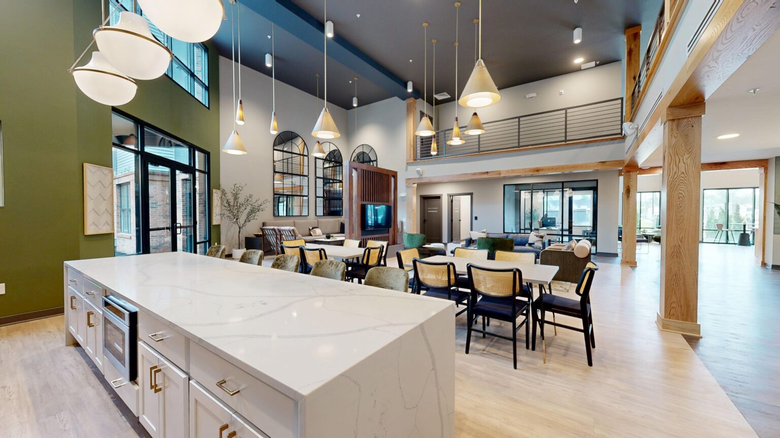 Modern open-concept lounge at Trace Quarter with high ceilings, pendant lights, a marble island, dining tables, seating area, large windows, and a mezzanine.