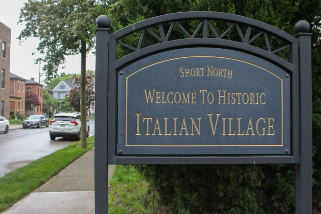Welcome to Historic Italian Village sign on a tree-lined residential street