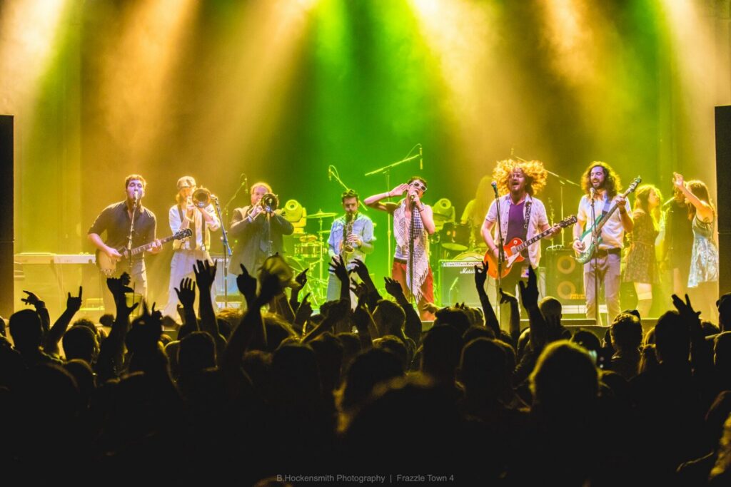 Thrive Companies, A band performs on stage under colorful lights as a crowd with raised hands cheers in the foreground. Apartments in Columbus Ohio