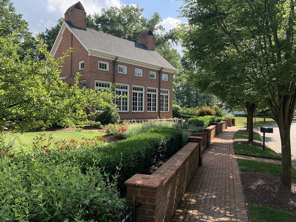 Georgian-style brick building and brick sidewalk lined with trees and gardens in New Albany, Ohio