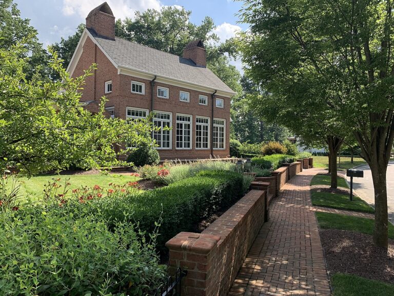 Georgian-style brick building and brick sidewalk lined with trees and gardens in New Albany