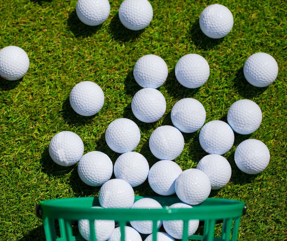 A group of white golf balls scattered on green grass with part of a green basket visible at the bottom of the image at The Michael at GVX.