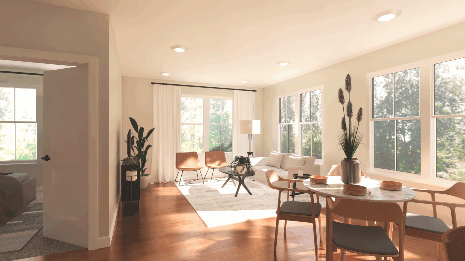 Bright, modern living and dining area at The Michael at GVX with wood floors, large windows, a round dining table, tan chairs, and neutral-toned decor; bedroom visible through open door.