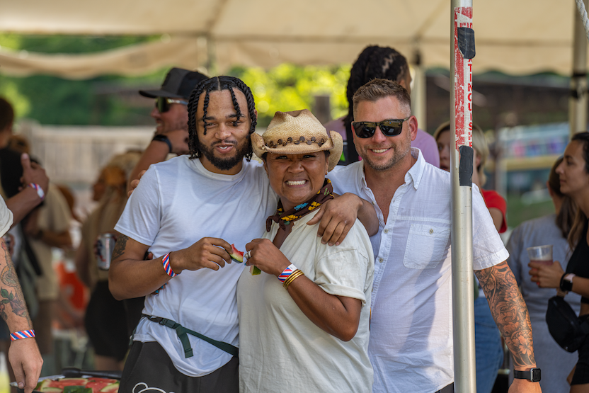 Thrive Companies, Three people stand together smiling under a tent at a Thrive Companies Ohio outdoor event, with others and food visible in the background. Apartments in Columbus Ohio