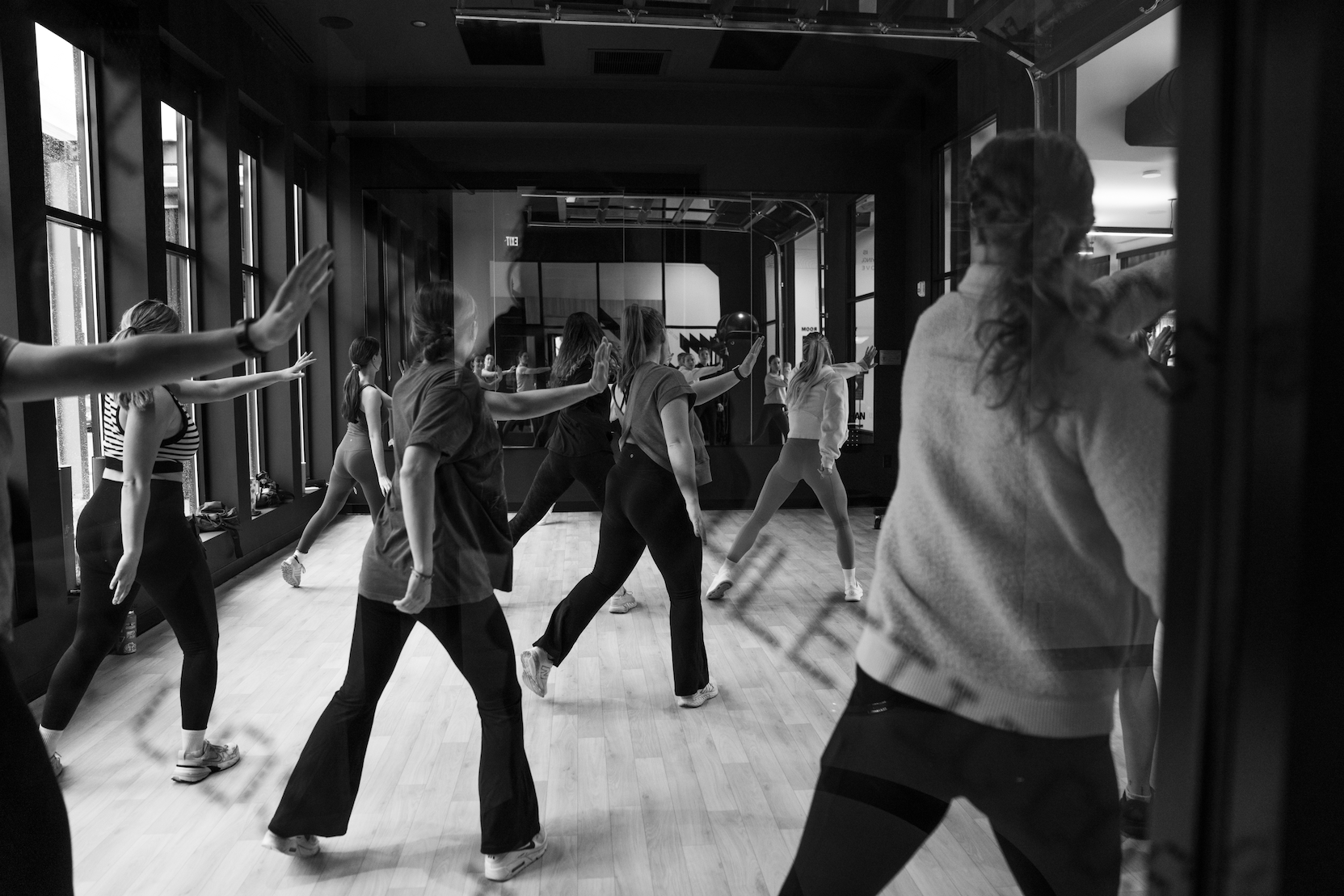 Thrive Companies, Our Team, dressed in casual athletic wear, participates in a lively dance or exercise class in a studio with large windows. Apartments in Columbus Ohio