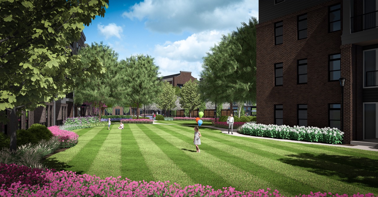 Thrive Companies, Children play with a ball on a neatly mowed lawn at Moore’s Edge, surrounded by flowerbeds and trees, with apartment buildings in the background under a partly cloudy sky. Apartments in Columbus Ohio