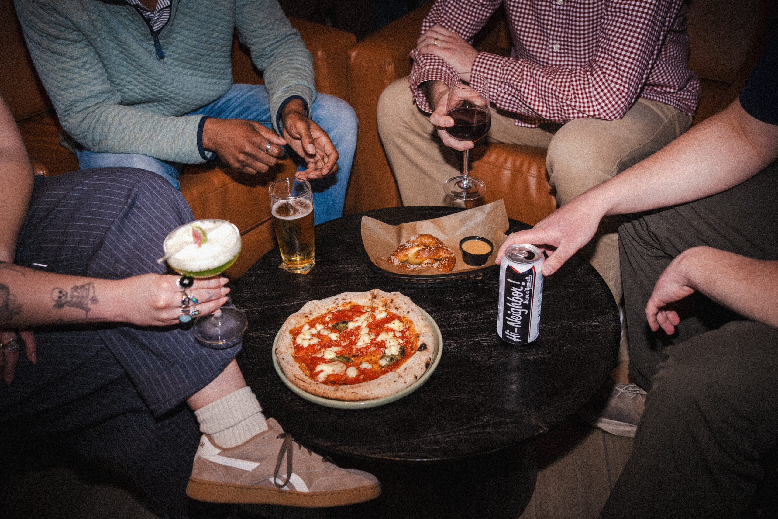Thrive Companies, Four people sitting around a small table at Bada Bar with a margherita pizza, a pretzel, and various drinks during a tasting. Apartments in Columbus Ohio