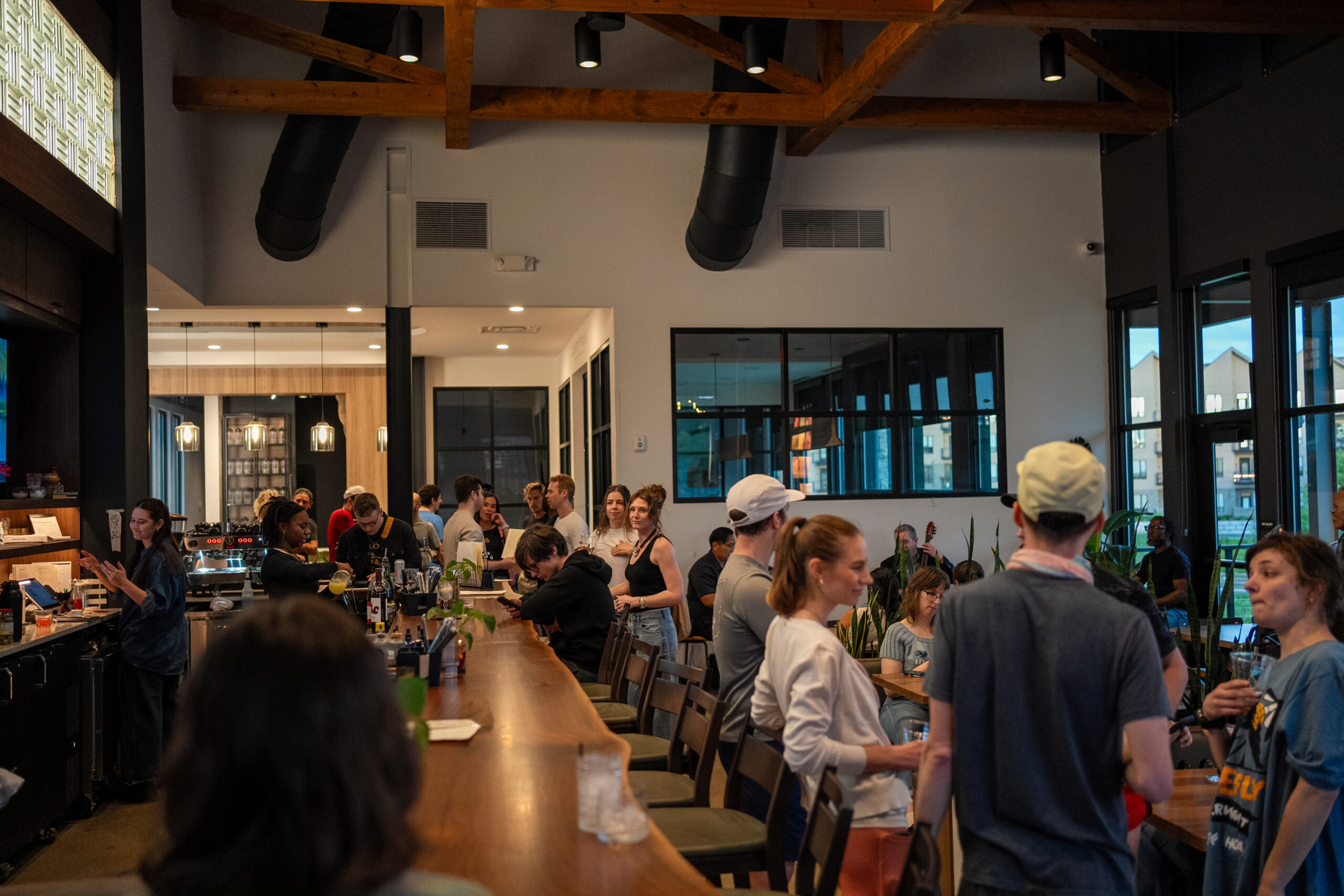 Thrive Companies, People gathering at the Bada Bar, a space featuring high ceilings and wooden beams. Apartments in Columbus Ohio